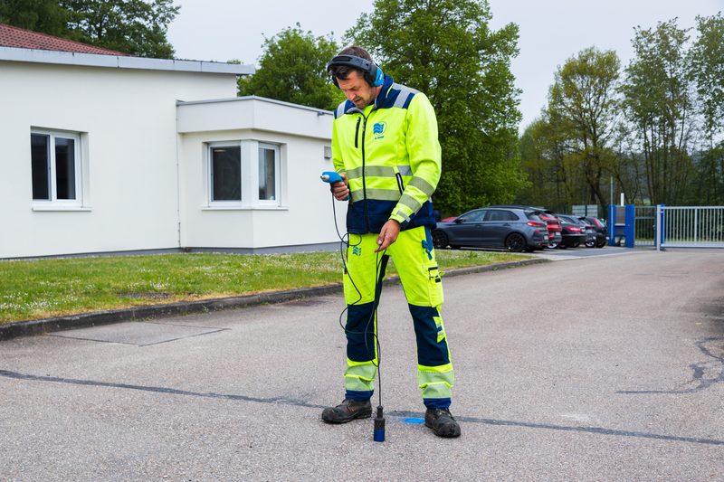 Mitarbeiter bei der Leckortung mit Kopfhörer am Bodenmikrofon